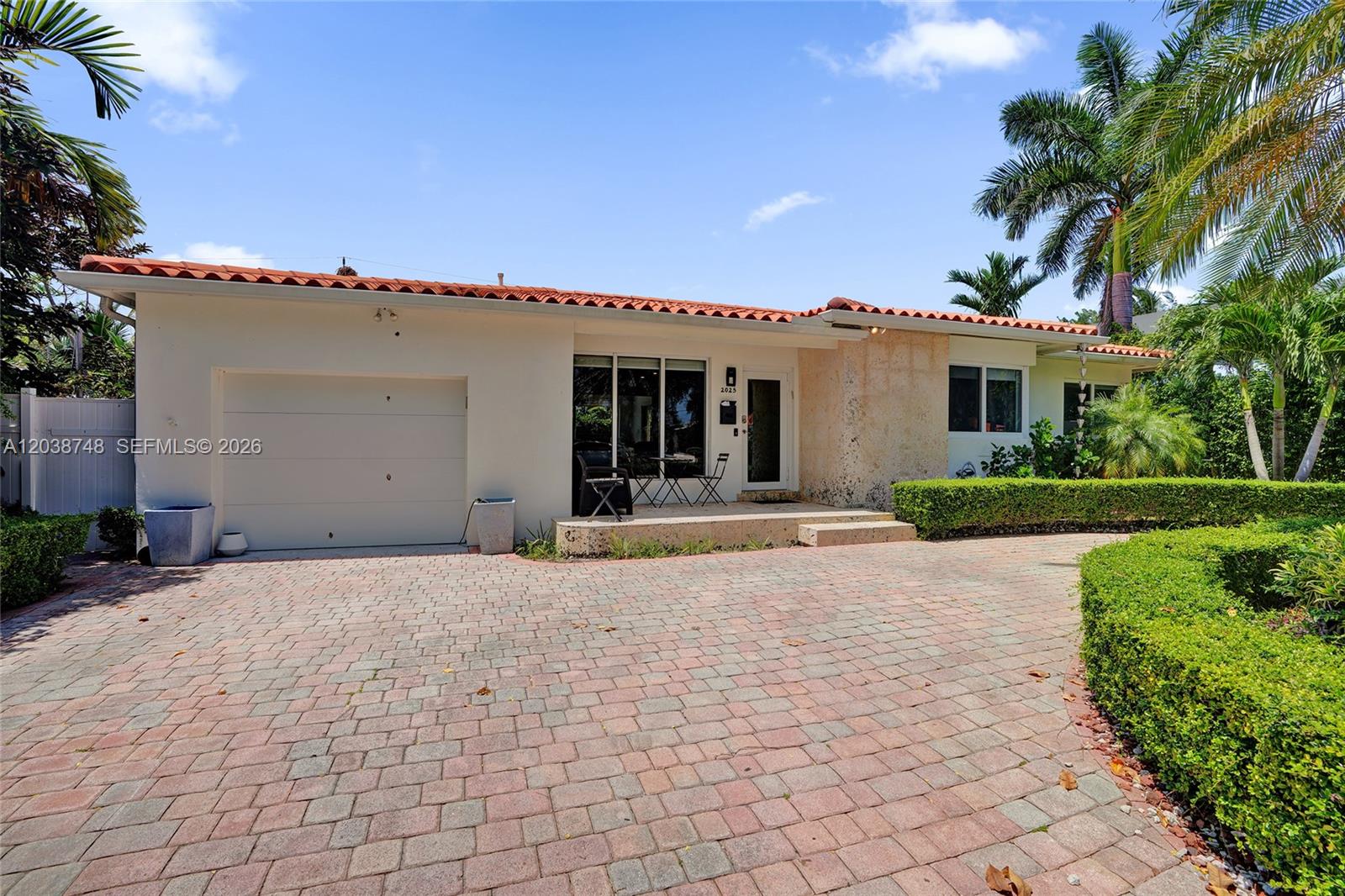 A single-story house with a red tile roof, brick driveway, and a stone-accented entryway — 2025 Alamanda Dr, North Miami FL 33181, NORTH MIAMI, FL