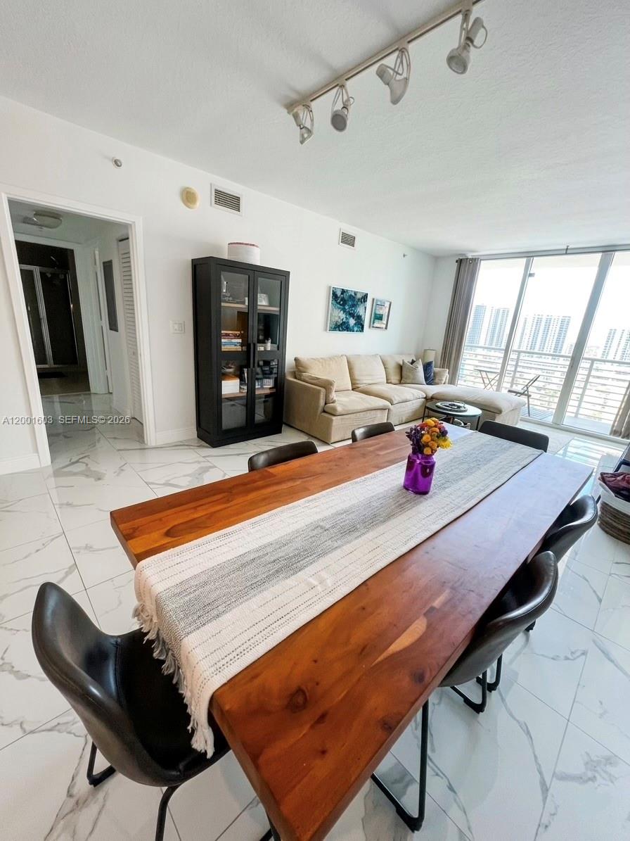 A dining area with a wooden table and black chairs opens into a living room — 335 S Biscayne Blvd # 3300, Miami FL 33131, MIAMI, FL