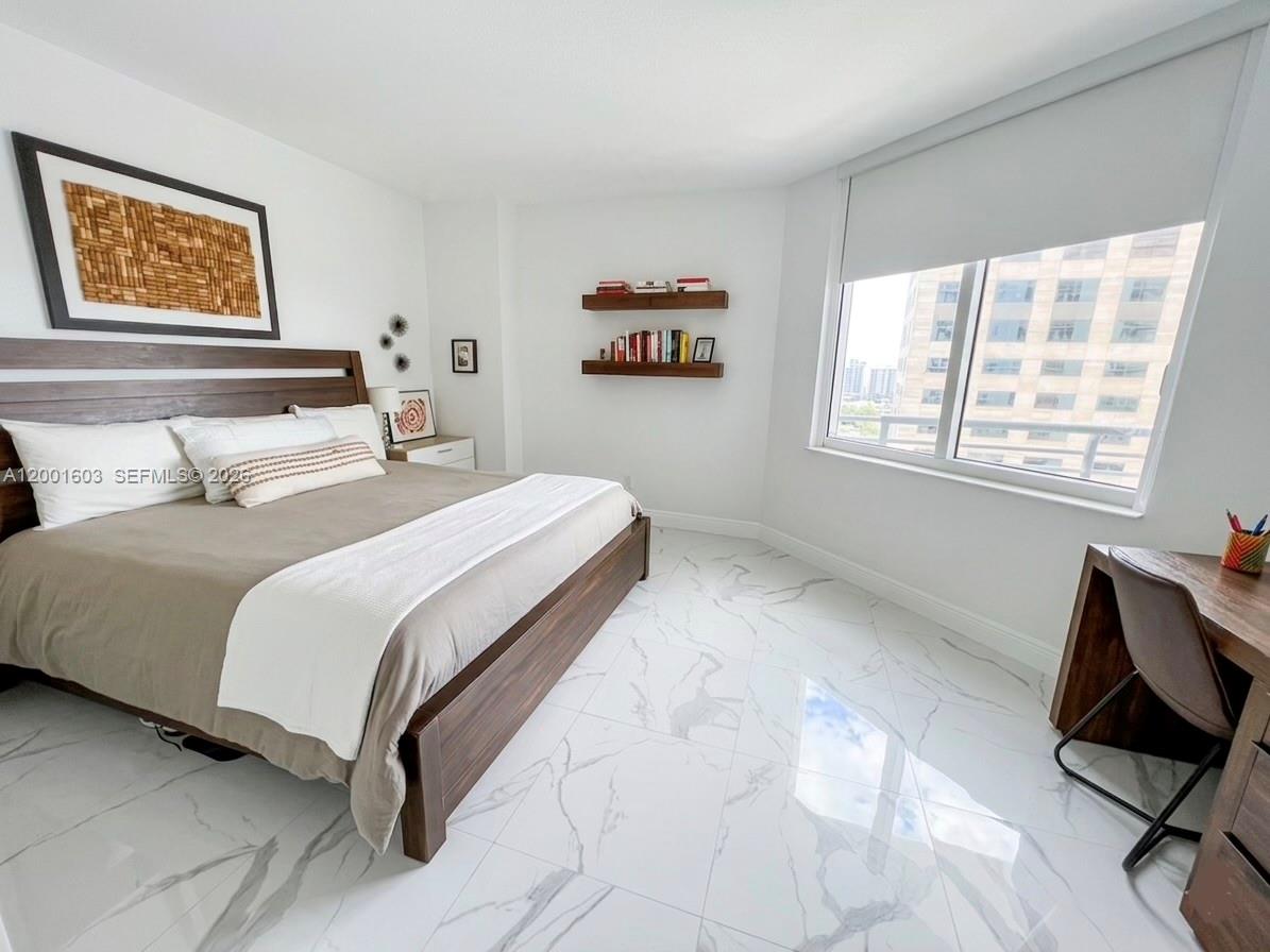 A bedroom features a wooden bed frame, white marble floors, floating shelves, and a desk — 335 S Biscayne Blvd # 3300, Miami FL 33131, MIAMI, FL