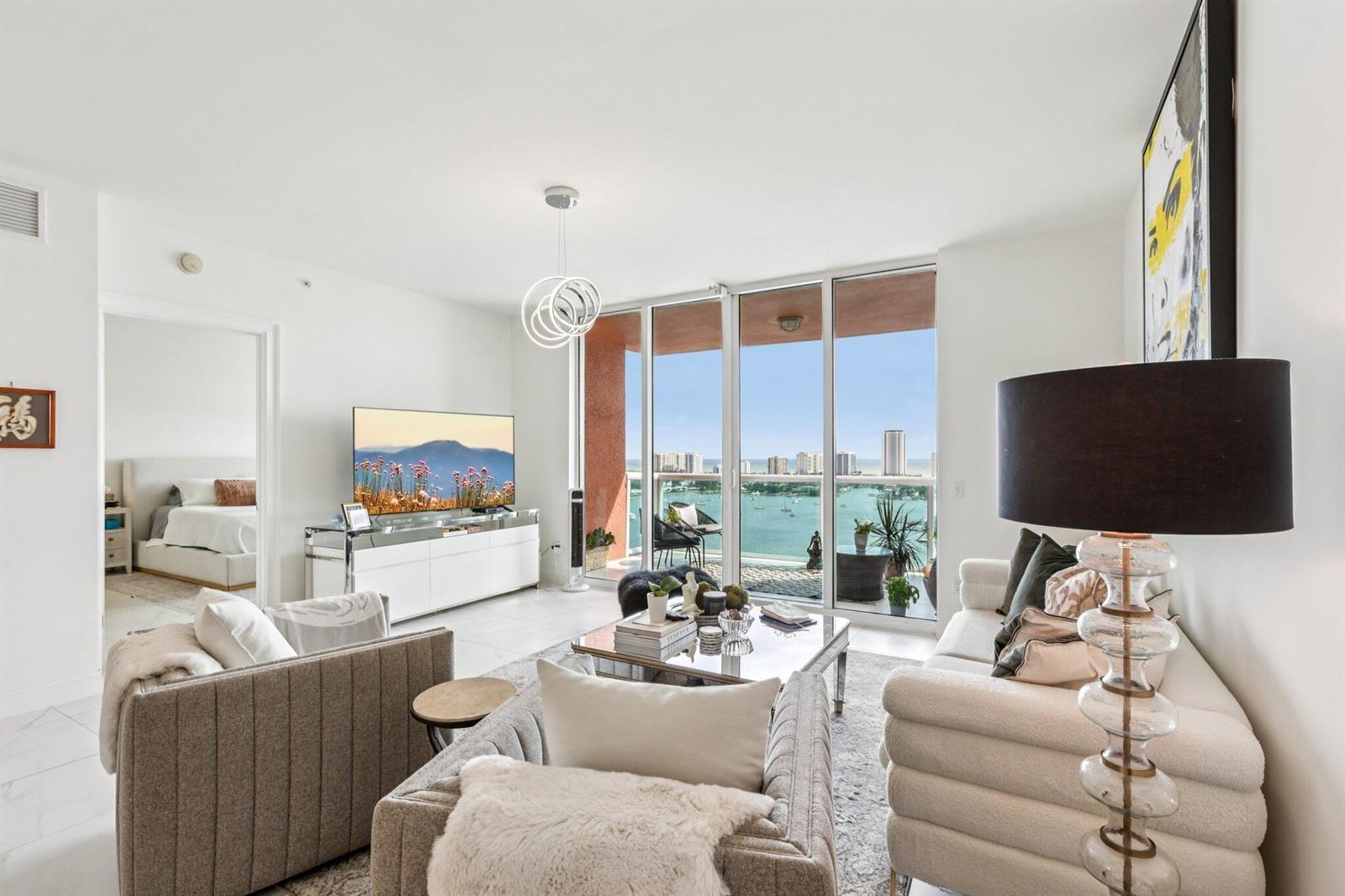 A modern living room features a white sofa, armchairs, and a balcony overlooking the ocean — 2640 Lake Shore Drive # 2008, Riviera Beach FL 33404, RIVIERA BEACH, FL