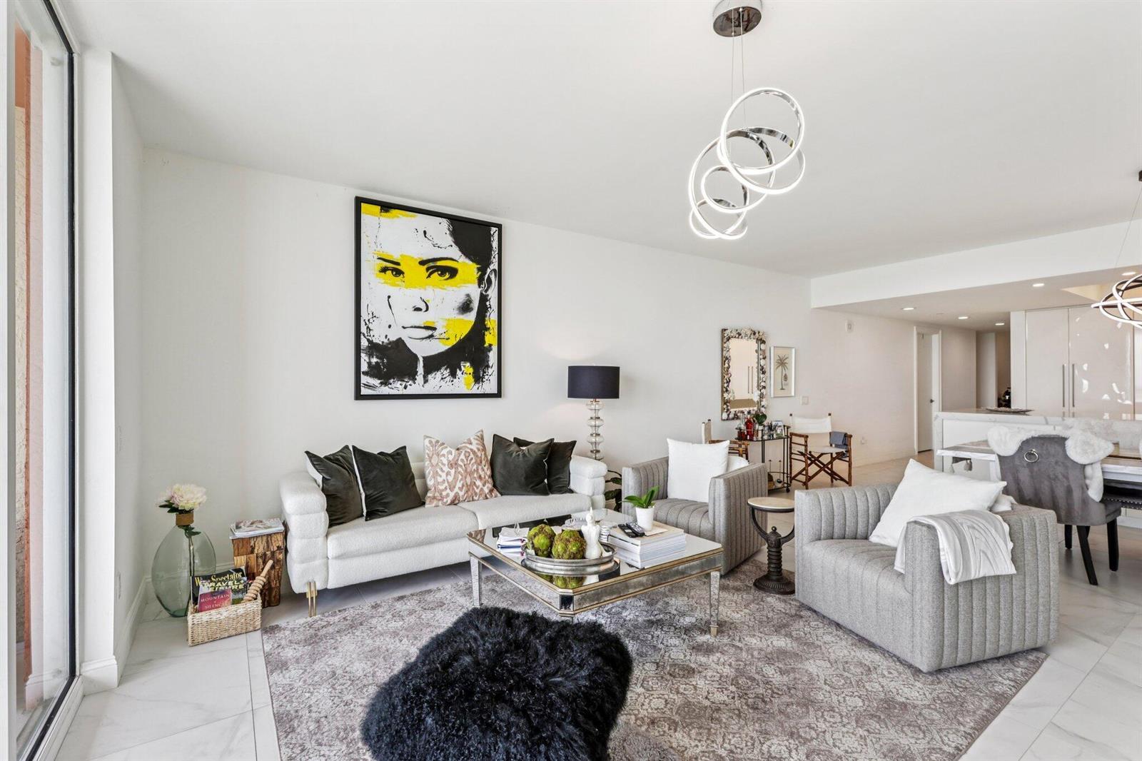 A modern living room features a white sofa, grey armchairs, and a large abstract portrait — 2640 Lake Shore Drive # 2008, Riviera Beach FL 33404, RIVIERA BEACH, FL