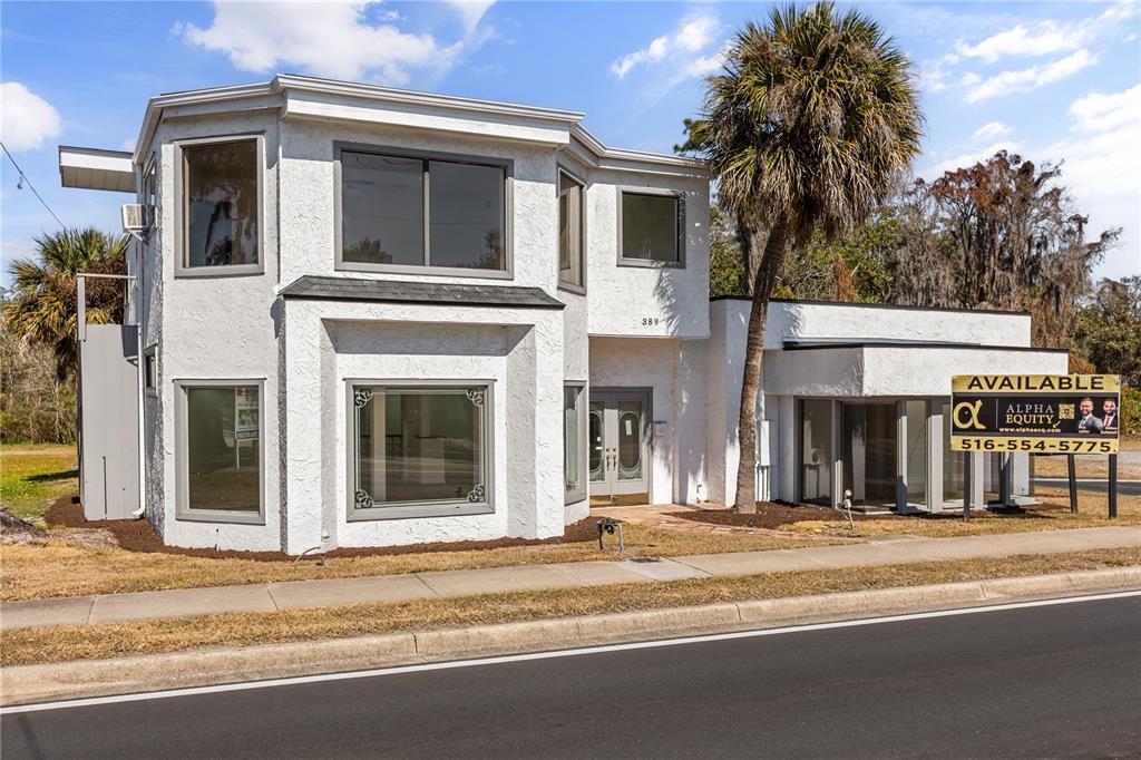 A two-story white stucco commercial building with large windows and a palm tree in front — 389 E STATE ROAD 434, LONGWOOD, FL