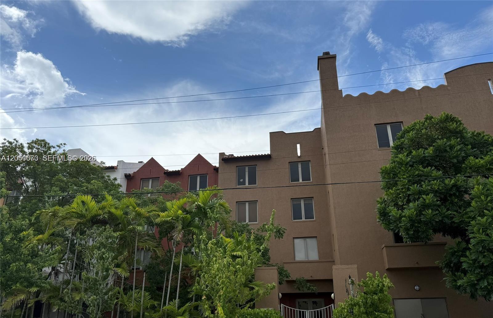 The exterior of a multi-story tan and red stucco building features a chimney and palm trees — 2630 SW 28th St # 34, Miami FL 33133, MIAMI, FL