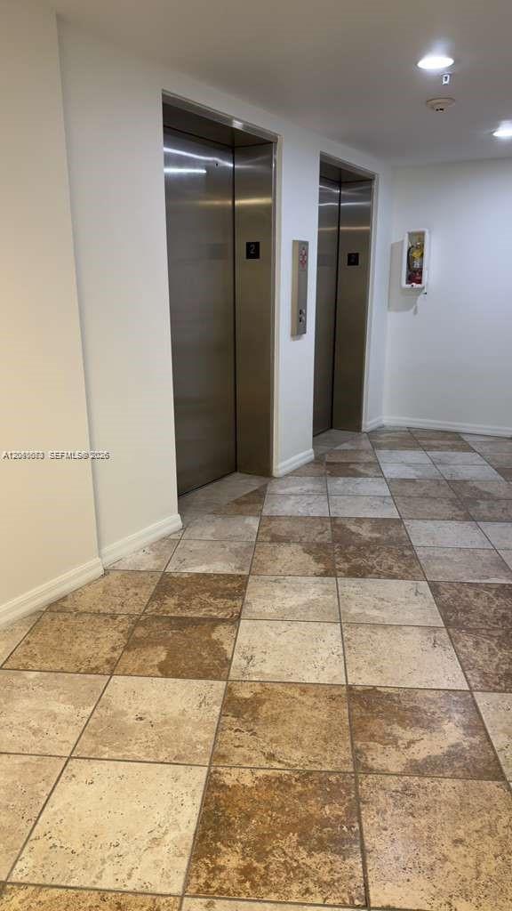 Two stainless steel elevators are set into a white wall above a tiled floor — 2630 SW 28th St # 34, Miami FL 33133, MIAMI, FL