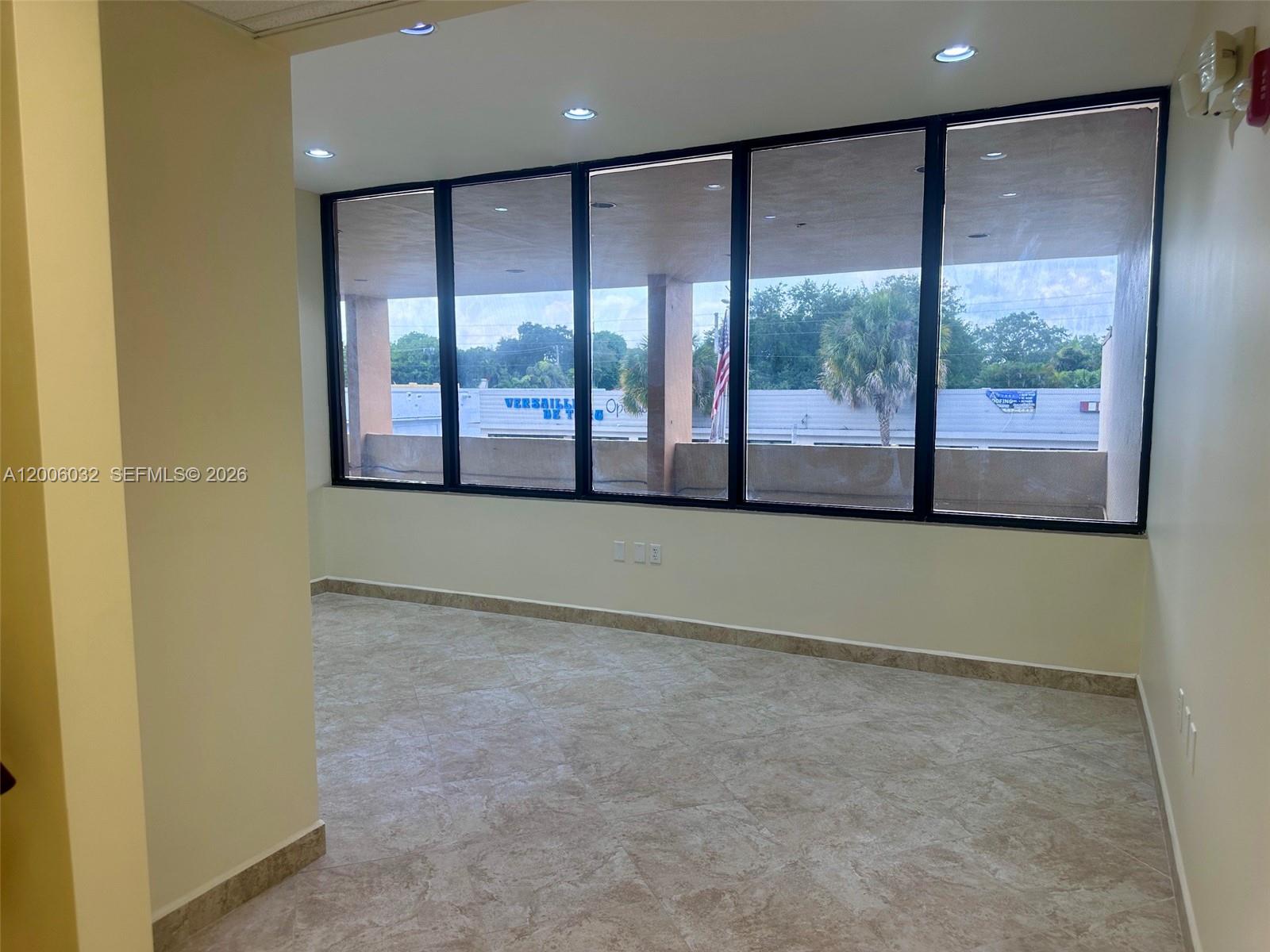 An empty office space features tile flooring, recessed lighting, and a wall of large windows — 5455 SW 8 ST # 215, Miami FL 33134, MIAMI, FL