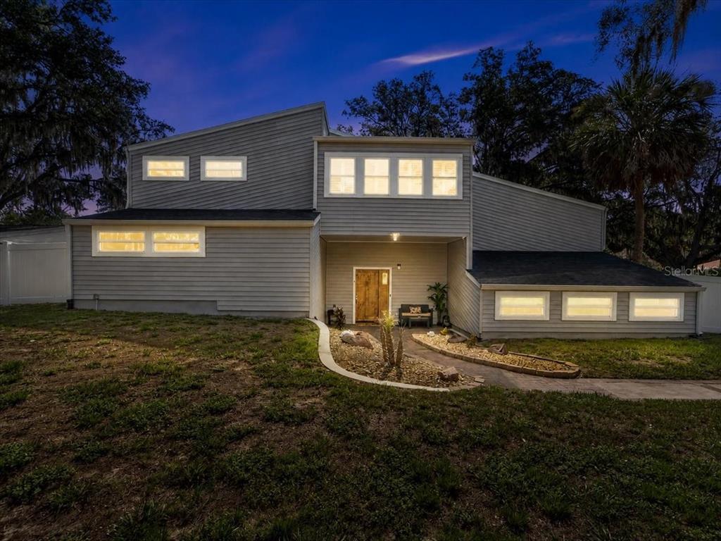 A two-story house with gray horizontal siding and a stone walkway at dusk — 11302 SANDPINE ROAD, RIVERVIEW, FL