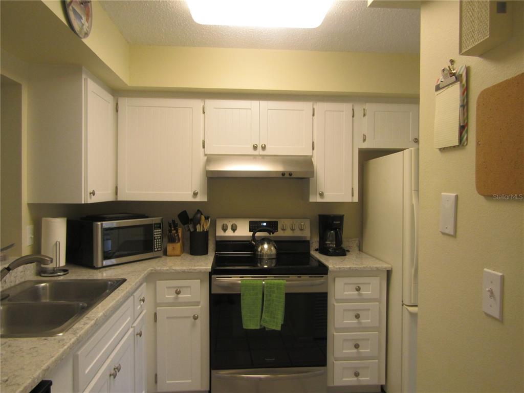 A kitchen features white cabinets, stainless steel appliances, and light-colored countertops — 7008 W COUNTRY CLUB DRIVE N UNIT 136, SARASOTA, FL