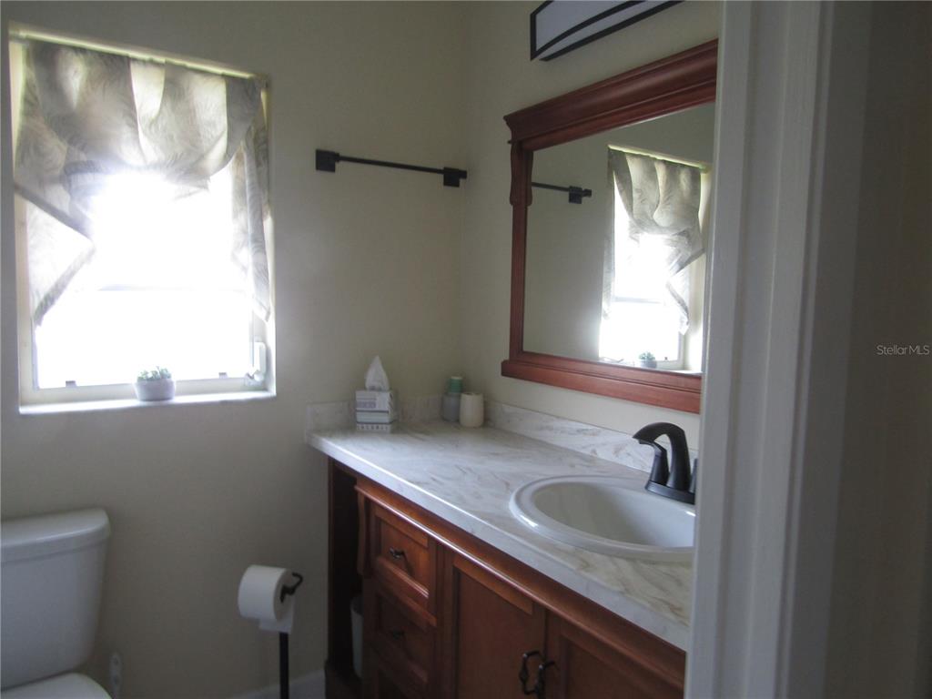 A bathroom features a wooden vanity with a marble-look countertop, a mirror, and a window — 7008 W COUNTRY CLUB DRIVE N UNIT 136, SARASOTA, FL
