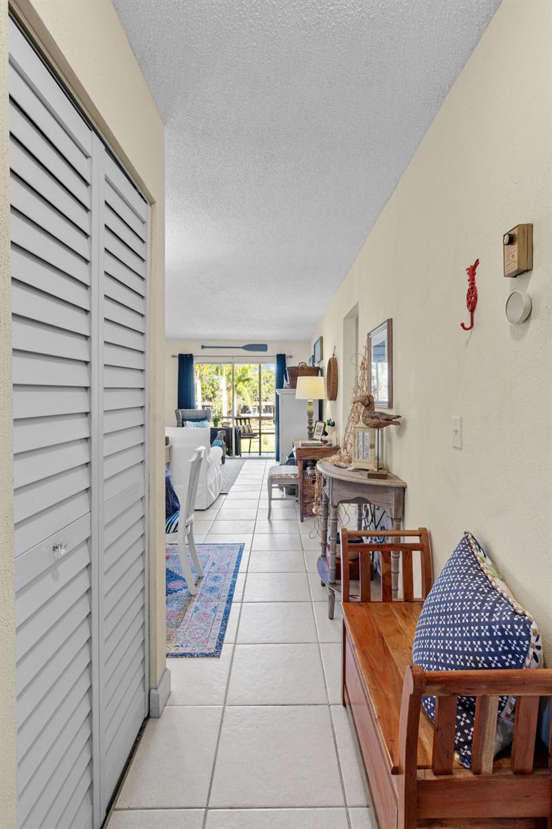 A hallway with tiled floors leads to a living area with a sliding glass door — 1967 SW Palm City Road # h, Stuart FL 34994, STUART, FL