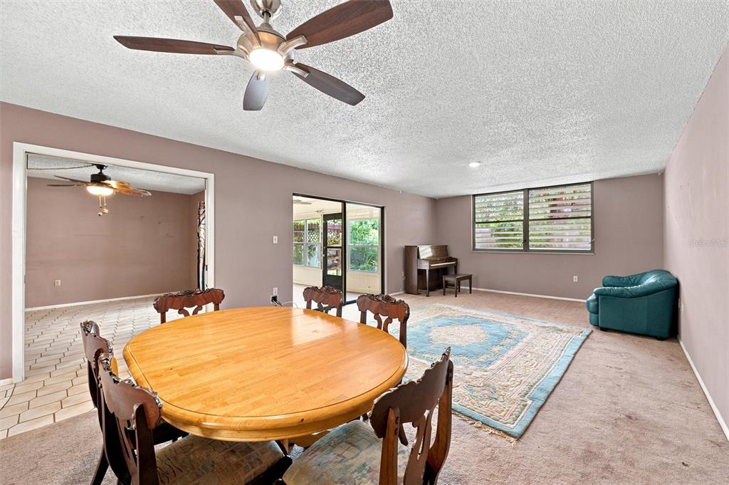 A dining area with a round table opens into a living room with a piano — 240 SHERWOOD DRIVE, BRADENTON, FL