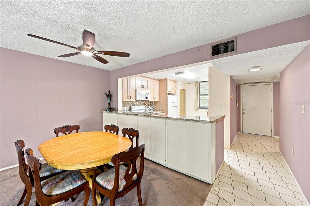 A dining area with a wooden table and chairs opens to a kitchen with cabinets — 240 SHERWOOD DRIVE, BRADENTON, FL