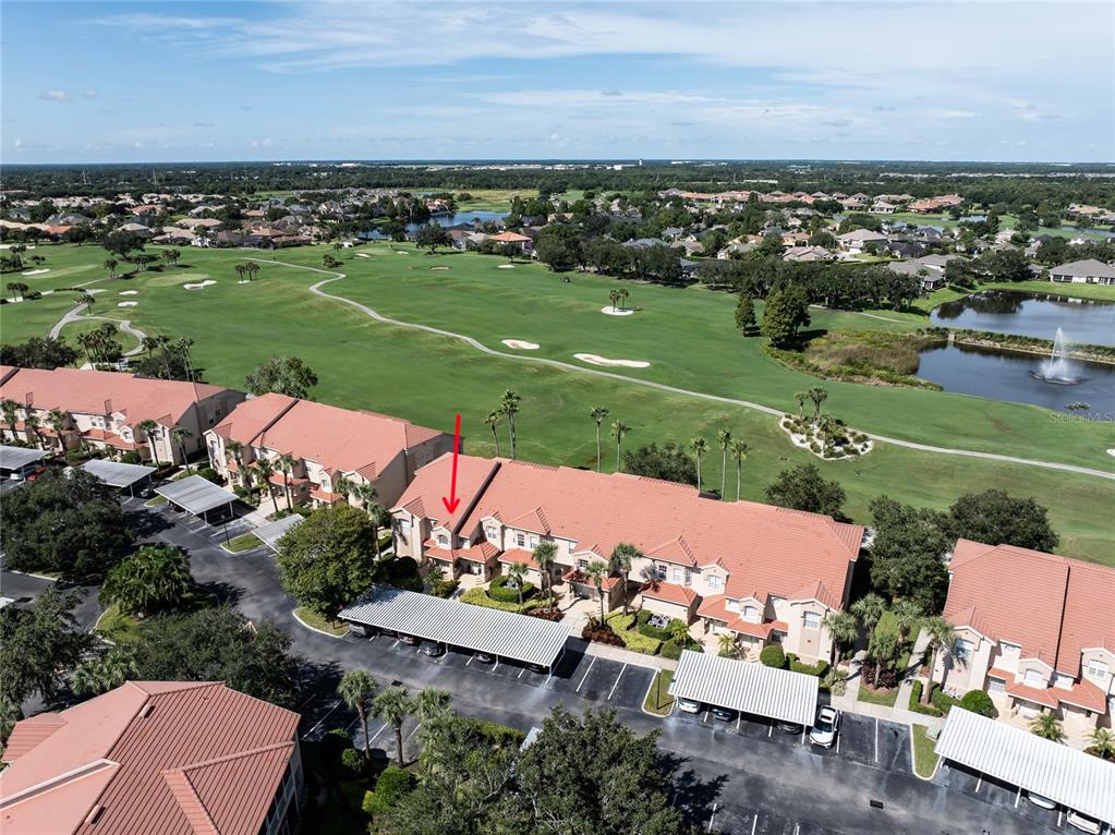 An aerial view shows a multi-story residential building with a red tile roof near a golf course — 447 ENCLAVE PLACE UNIT 447, LAKELAND, FL