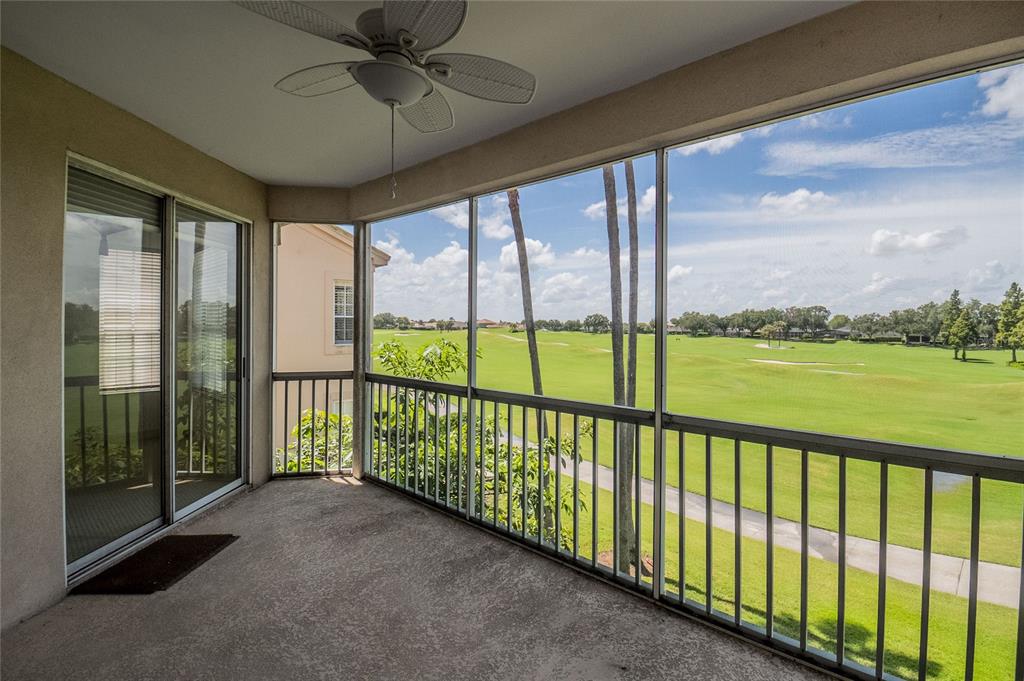 A screened-in balcony with a ceiling fan overlooks a green golf course — 447 ENCLAVE PLACE UNIT 447, LAKELAND, FL