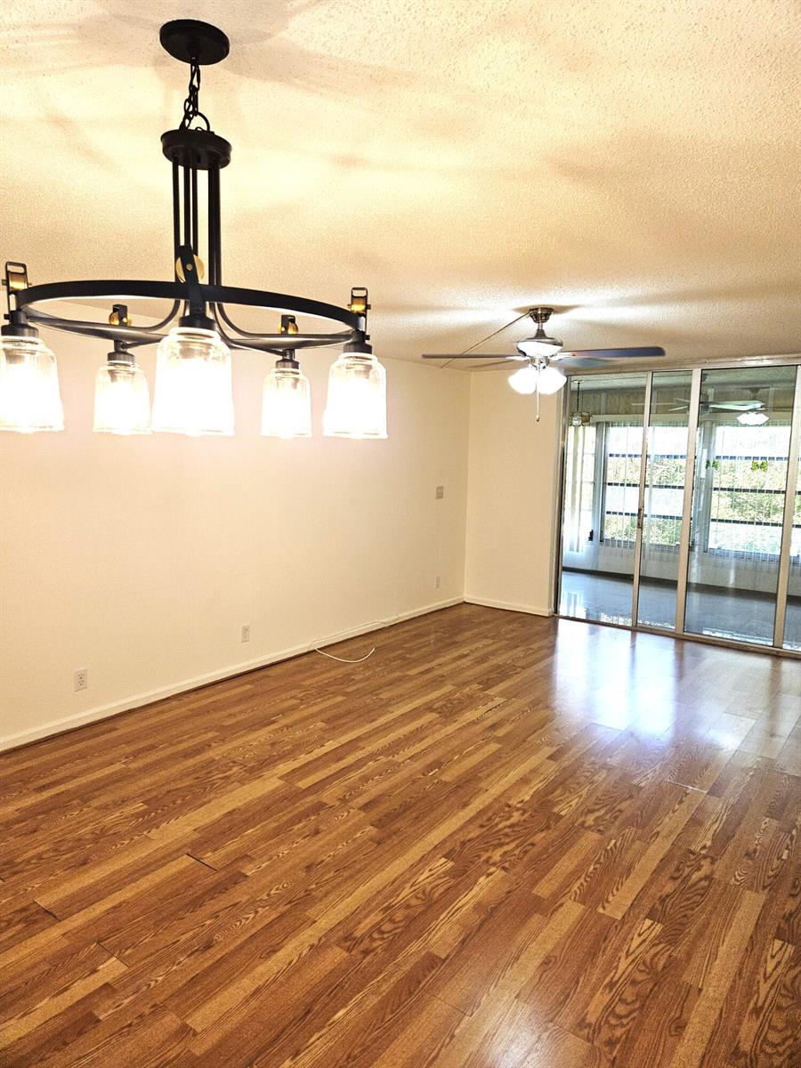 A dining area with hardwood floors, a modern chandelier, and sliding glass doors to a balcony — 357 N Rock Island Road # 407, Margate FL 33063, MARGATE, FL