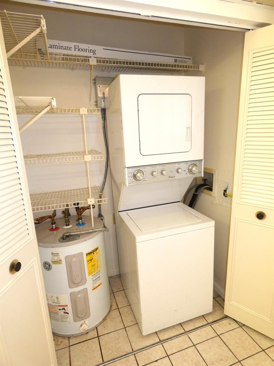 A closet contains a stacked washer and dryer unit next to a water heater — 357 N Rock Island Road # 407, Margate FL 33063, MARGATE, FL