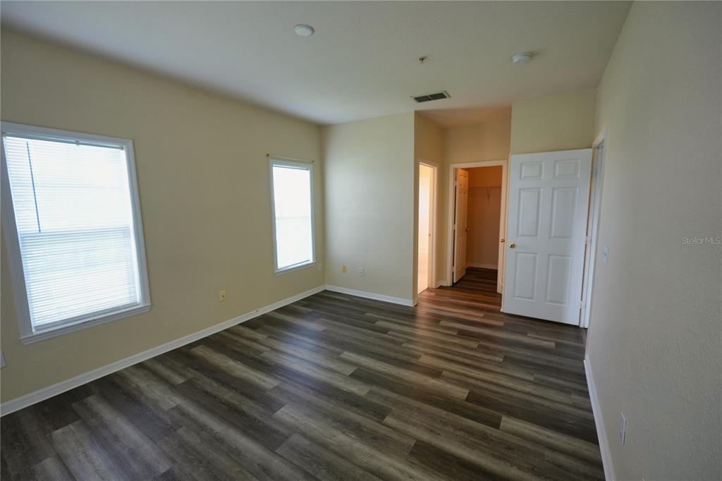 An empty bedroom features light-colored walls, two windows, and dark wood-look plank flooring — 3757 CONROY RD UNIT 2531, ORLANDO, FL