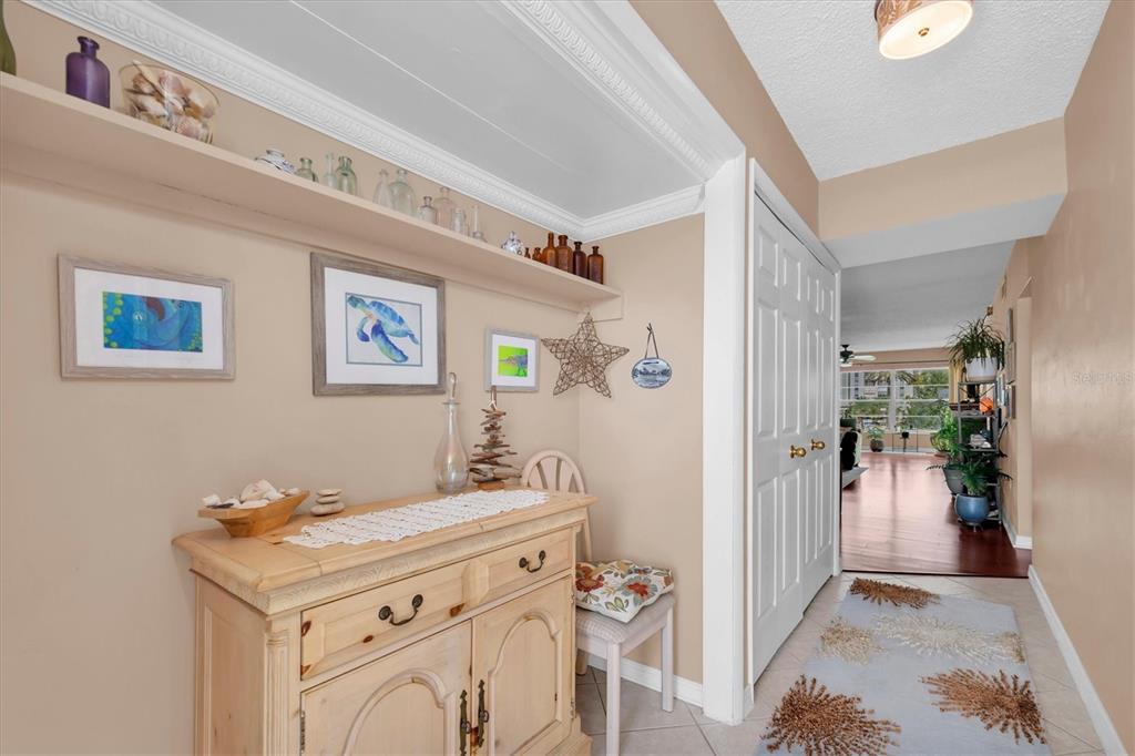 A hallway features a light wood cabinet, a built-in shelf, and a view into a living area — 6363 GULF WINDS DRIVE UNIT 233, ST PETERSBURG, FL