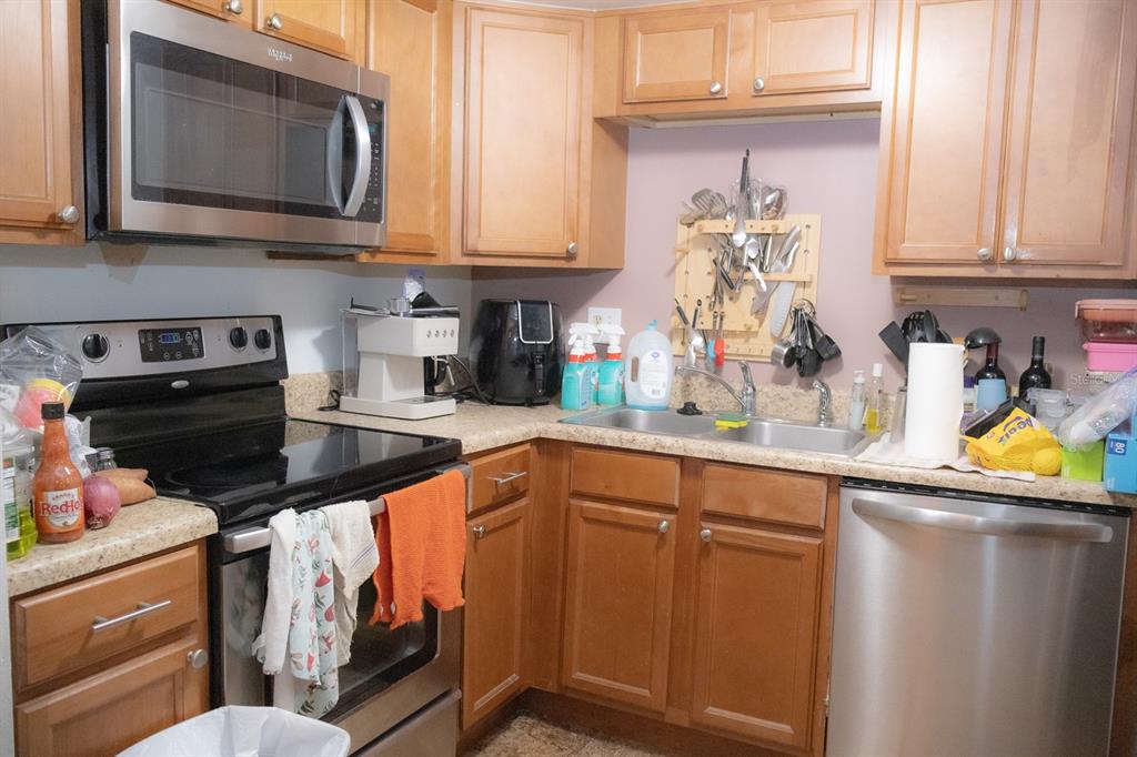A kitchen features wood cabinets, stainless steel appliances, and laminate countertops — 922 LAKE DESTINY ROAD UNIT H, ALTAMONTE SPRINGS, FL