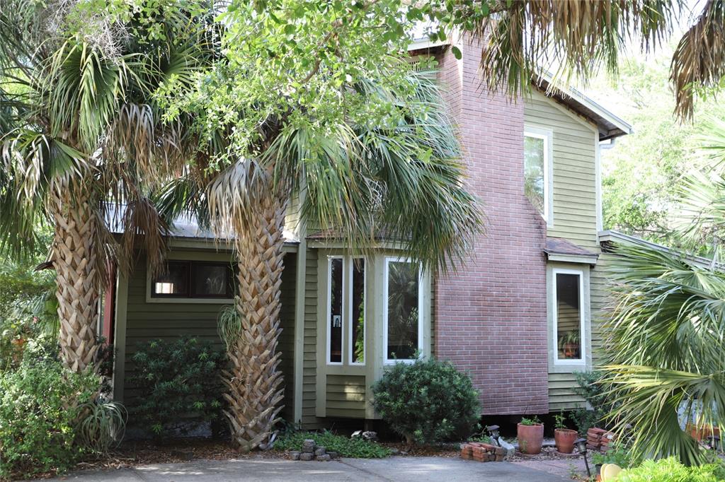 A two-story house with green siding, a brick chimney, and palm trees in the front — 272 ORANGE STREET UNIT A-B, PALM HARBOR, FL