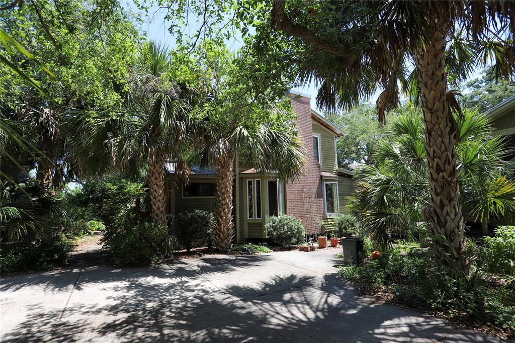 A two-story house with a brick chimney and palm trees sits behind a concrete driveway — 272 ORANGE STREET UNIT A-B, PALM HARBOR, FL