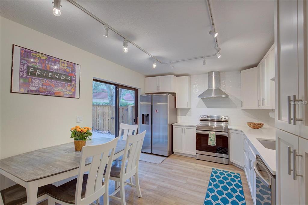 A kitchen with white cabinets, stainless steel appliances, and a dining table near a sliding door — 2612 2ND COURT, PALM HARBOR, FL