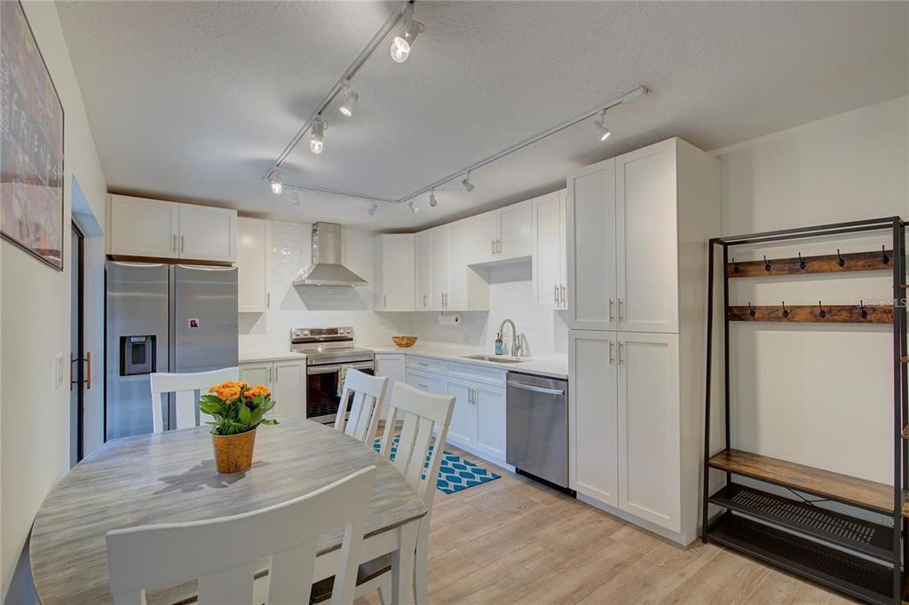 A kitchen features white cabinetry, stainless steel appliances, track lighting, and an adjacent dining area — 2612 2ND COURT, PALM HARBOR, FL