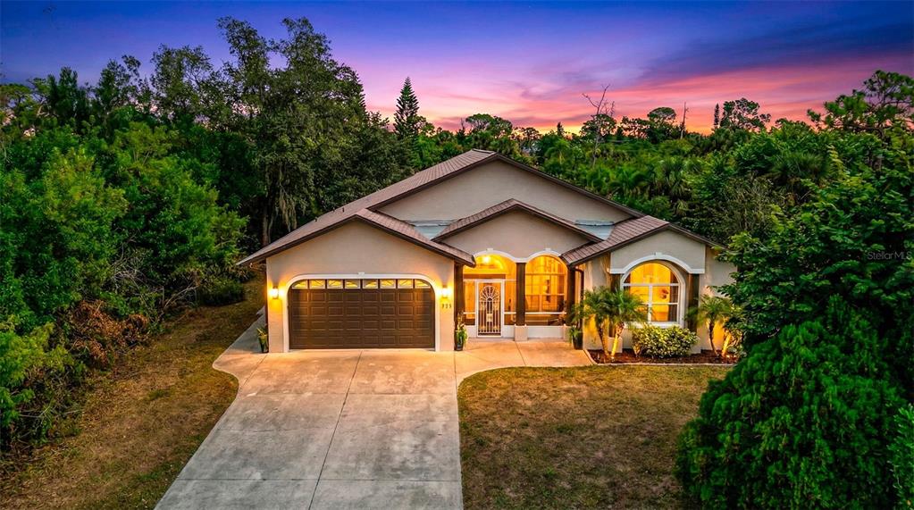 A single-story house with a two-car garage and arched windows stands at dusk — 333 ORDUNA DRIVE, NORTH PORT, FL