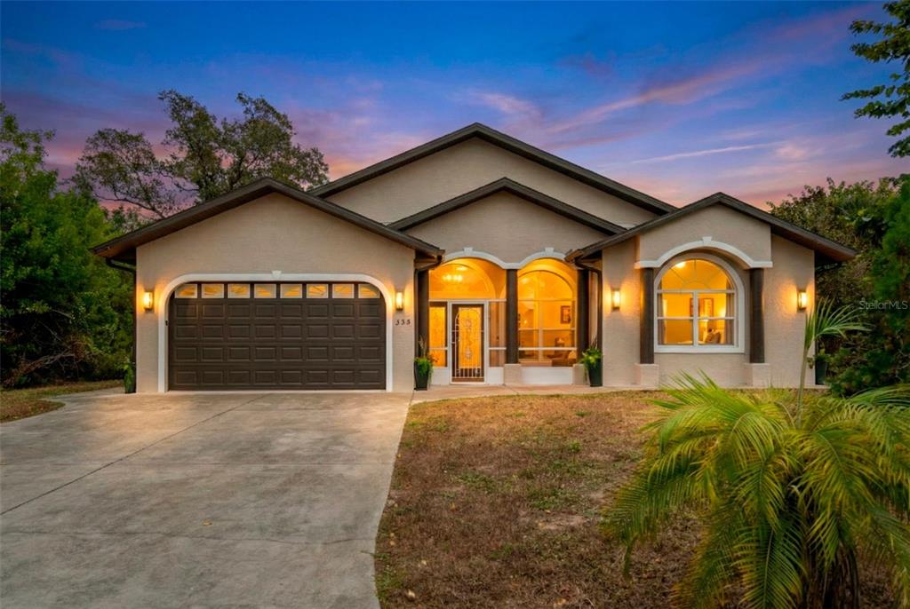 A single-story house with a two-car garage, arched windows, and a concrete driveway at dusk — 333 ORDUNA DRIVE, NORTH PORT, FL