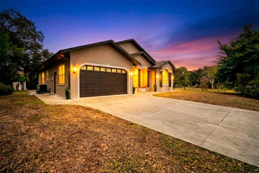 A single-story house with a two-car garage and a concrete driveway at sunset — 333 ORDUNA DRIVE, NORTH PORT, FL