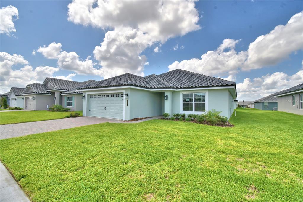 A light green single-story house with a tiled roof and a two-car garage — 4657 GRANDVIEW GLEN DRIVE, AUBURNDALE, FL