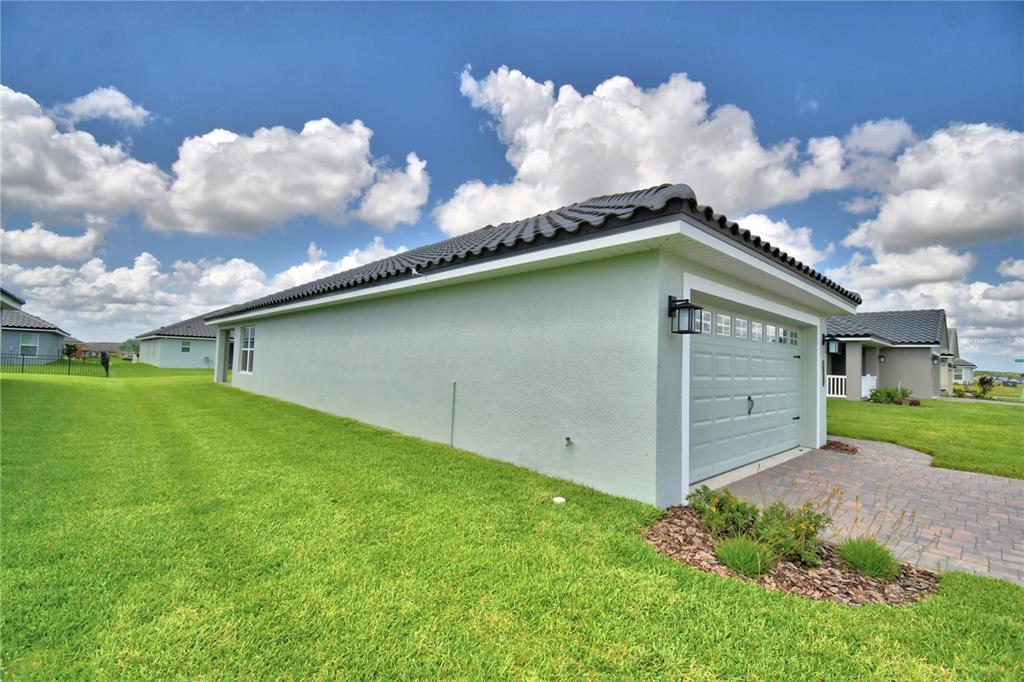 The exterior side and garage of a light green house with a dark tiled roof — 4657 GRANDVIEW GLEN DRIVE, AUBURNDALE, FL
