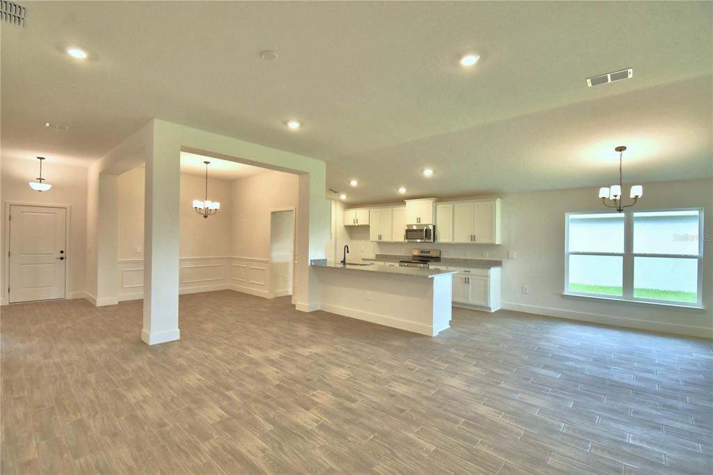 An open-concept kitchen and dining area with white cabinetry, a central island, and tile flooring — 4657 GRANDVIEW GLEN DRIVE, AUBURNDALE, FL