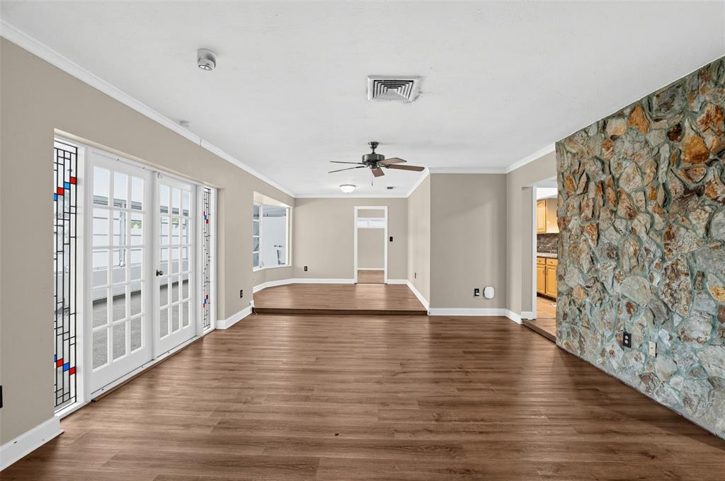 A living room features wood-look flooring, a stone accent wall, and glass-paned French doors — 6450 31ST TERRACE N, ST PETERSBURG, FL