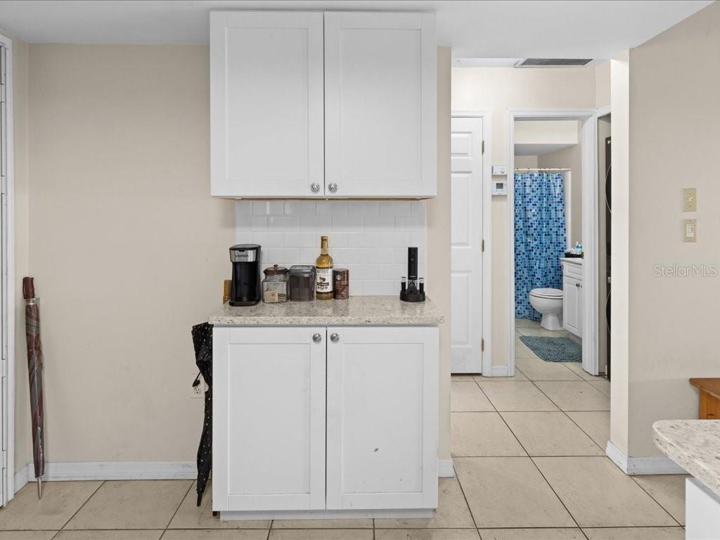 A white kitchen cabinet unit with a speckled countertop stands against a tiled wall — 25275 RAMPART BOULEVARD UNIT 1607, PUNTA GORDA, FL