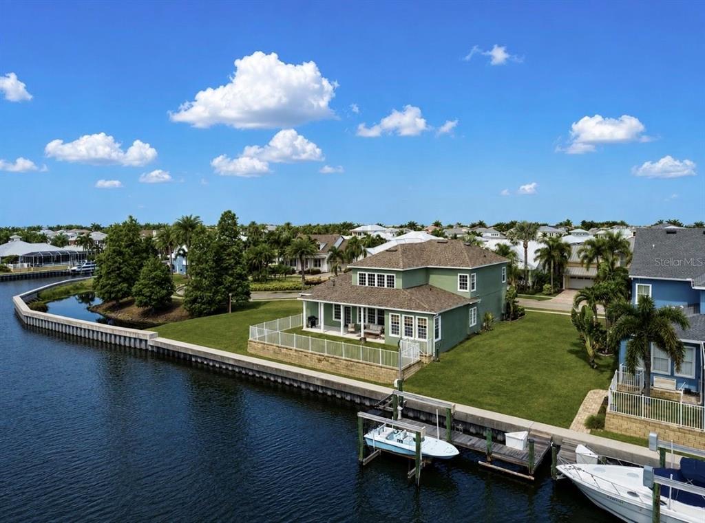 An aerial view of a green two-story house situated on a canal with boat docks — 5709 SEA TROUT PLACE, APOLLO BEACH, FL