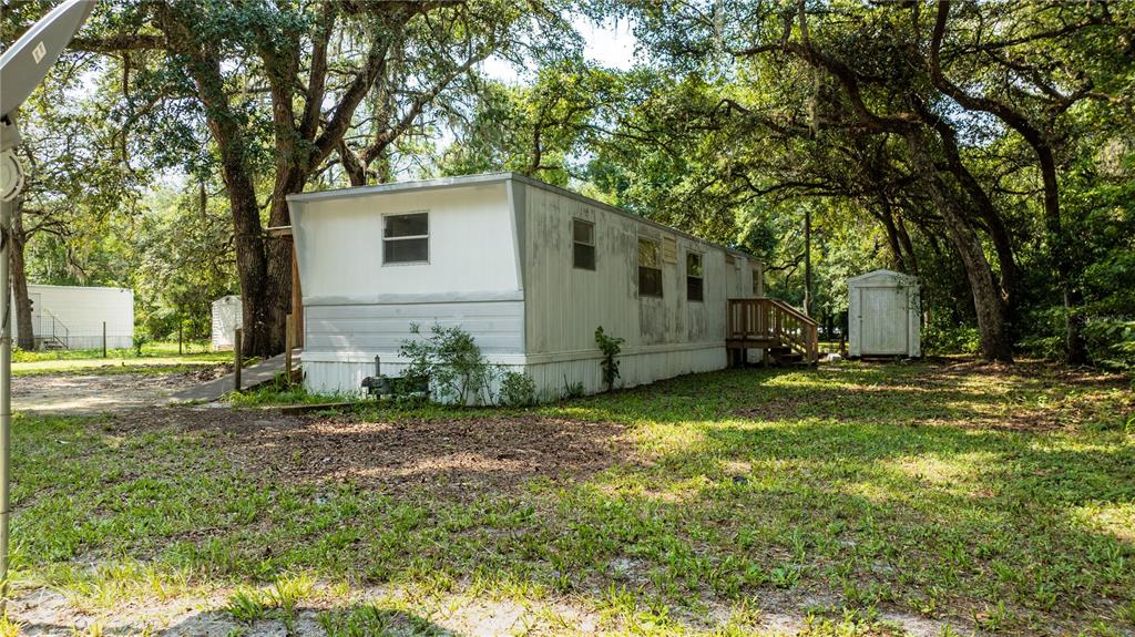 A weathered mobile home sits on a grassy lot surrounded by mature trees — 49 NE 472ND AVENUE, OLD TOWN, FL