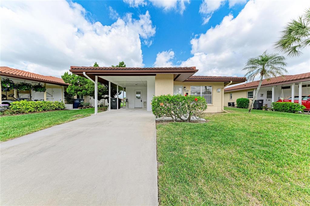 A single-story house with a carport, a concrete driveway, and a lawn under a cloudy sky — 3303 CHICAGO AVENUE, BRADENTON, FL