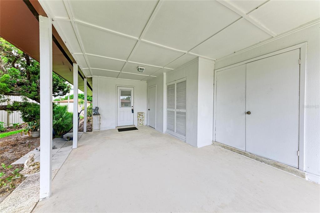 A covered concrete patio features white walls, a door, and several storage closets — 3303 CHICAGO AVENUE, BRADENTON, FL
