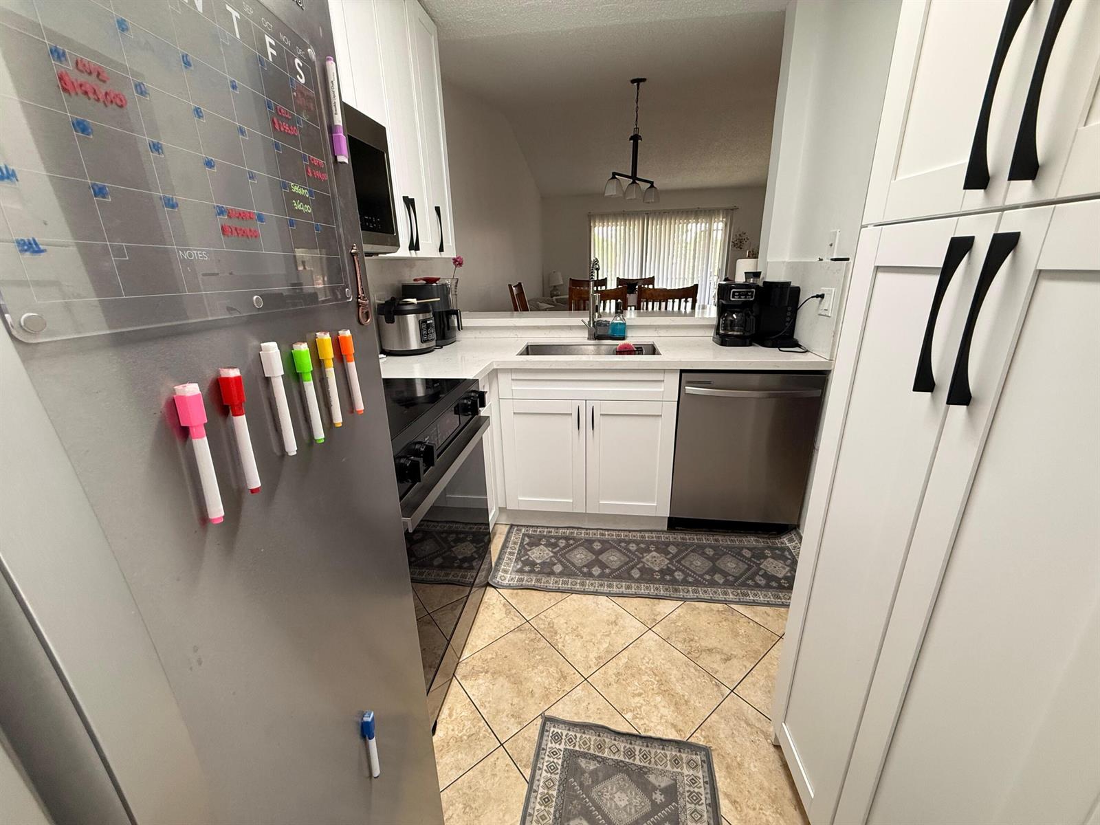 A kitchen features white cabinets, stainless steel appliances, a sink, and tile flooring — 9923 Three Lakes Circle # h, Boca Raton FL 33428, BOCA RATON, FL