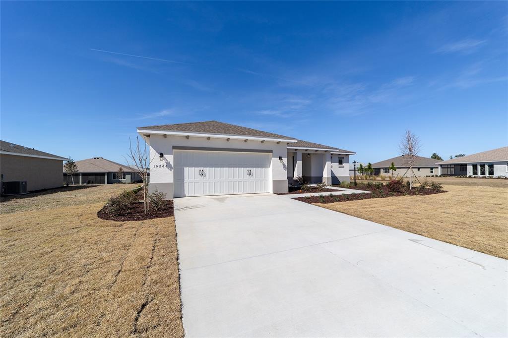A single-story house with a white stucco exterior and a two-car garage — 10268 SW 105TH TERRACE, OCALA, FL