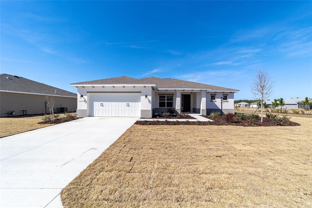 A single-story house with a white stucco exterior, a two-car garage, and a brown roof — 10268 SW 105TH TERRACE, OCALA, FL