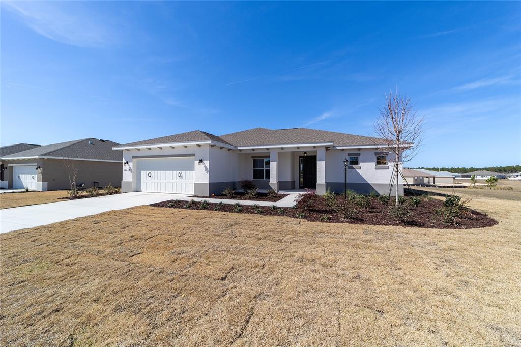 A single-story house with a two-car garage, light stucco exterior, and a brown shingled roof — 10268 SW 105TH TERRACE, OCALA, FL