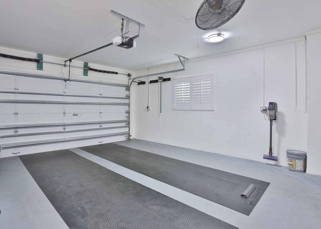 A clean garage with white walls, a sectional door, and two black floor mats — 713 Forsyth Street, Boca Raton FL 33487, BOCA RATON, FL