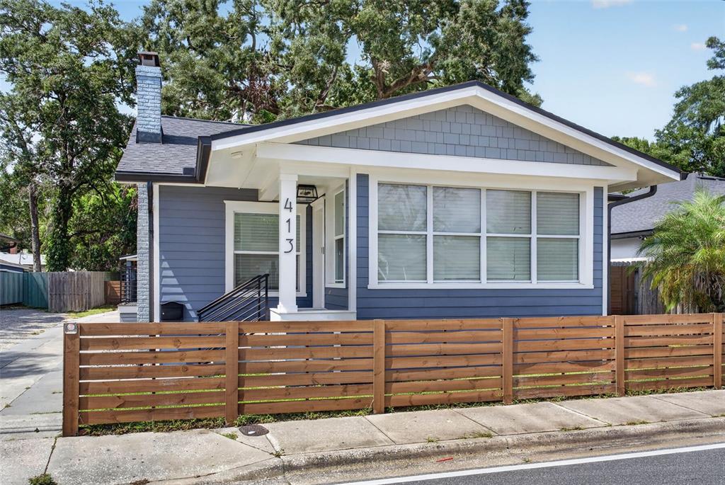 A blue bungalow with a wooden horizontal fence, a front porch, and a brick chimney — 413 W PRINCETON STREET, ORLANDO, FL