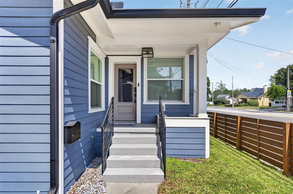 A blue house exterior features a front porch with concrete steps and a black railing — 413 W PRINCETON STREET, ORLANDO, FL