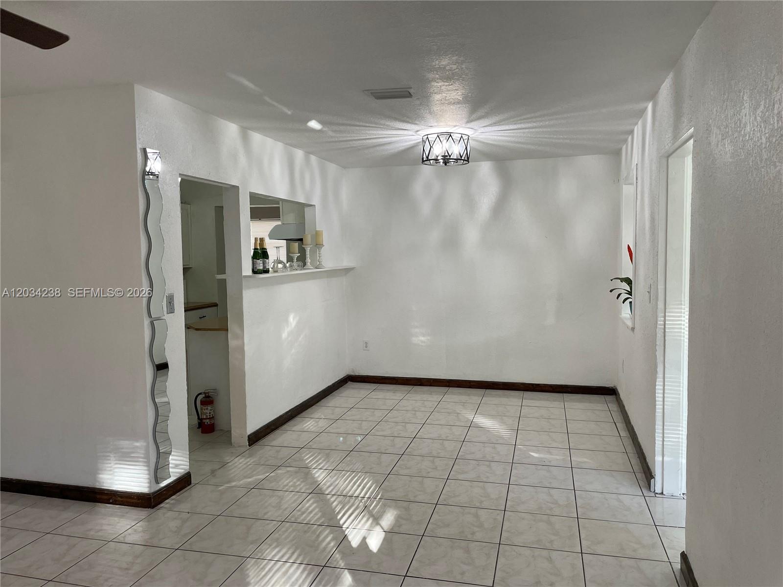 A dining room with white walls, tiled floors, a decorative mirror, and a ceiling light — 3389 William Ave # 0, Miami FL 33133, MIAMI, FL
