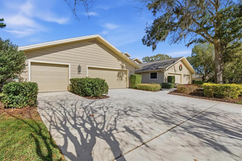 A tan house with a two-car garage and a concrete driveway under a blue sky — 1127 ROYAL TROON COURT, TARPON SPRINGS, FL