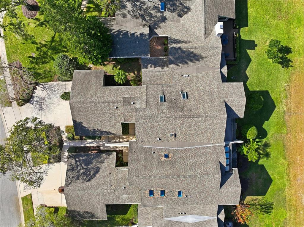 An aerial view shows the shingled roof of a large residential building with multiple skylights — 1127 ROYAL TROON COURT, TARPON SPRINGS, FL