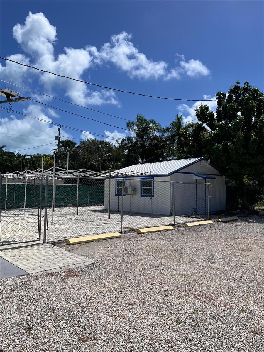 A small white building with a metal roof sits behind a chain-link fence — 91461 Overseas Hwy, Tavernier FL 33070, TAVERNIER, FL