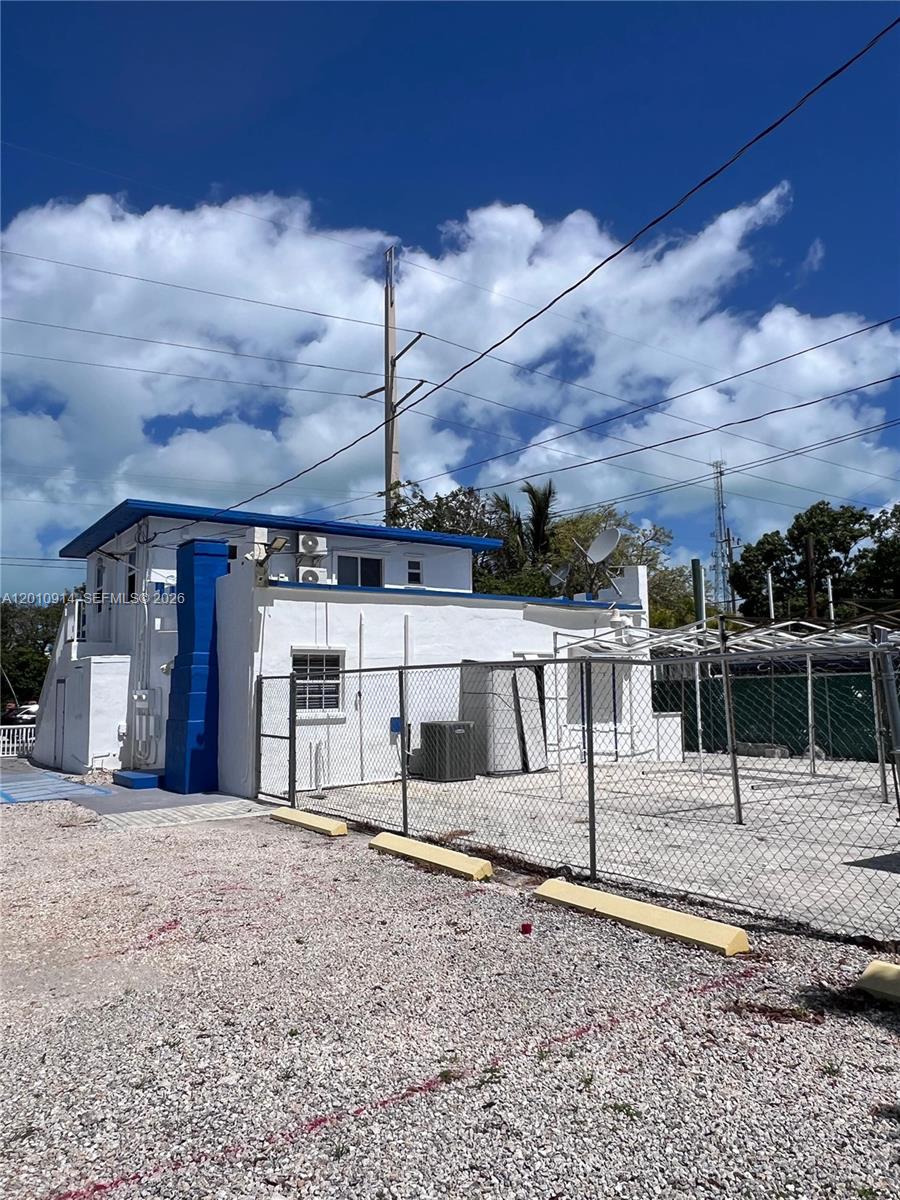 A white building with a blue roof and trim stands behind a chain-link fence — 91461 Overseas Hwy, Tavernier FL 33070, TAVERNIER, FL